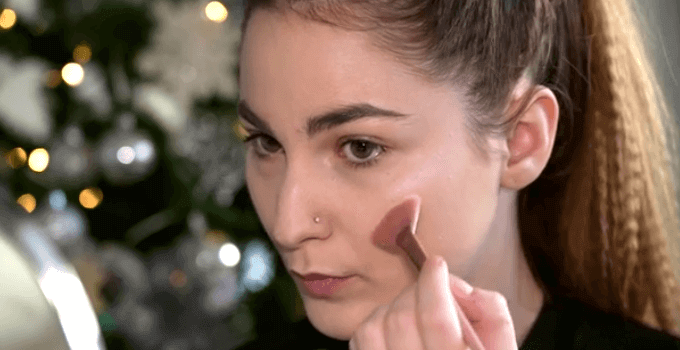 girl applying highlighter on top of cheekbone
