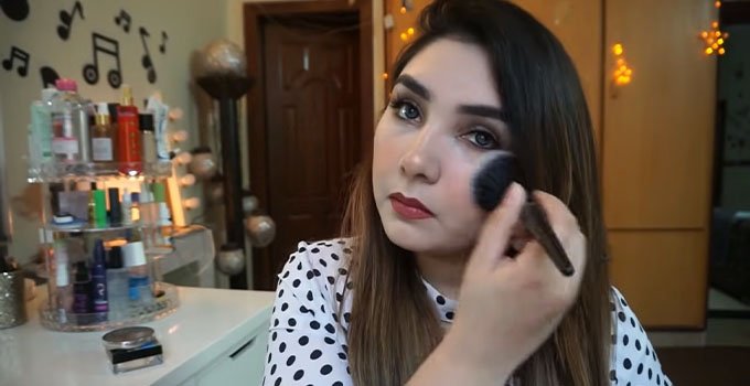 A girl apply face powder on her face with Brush