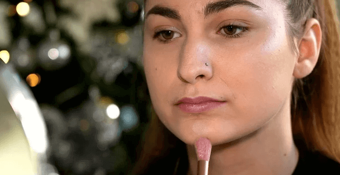 girl applying highlighter on her chin