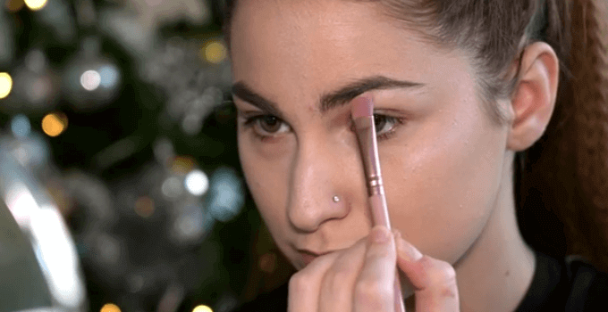 girl applying highlighter under her eyebrows
