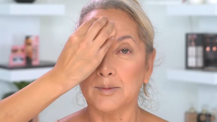 Applying blush on mature face forehead